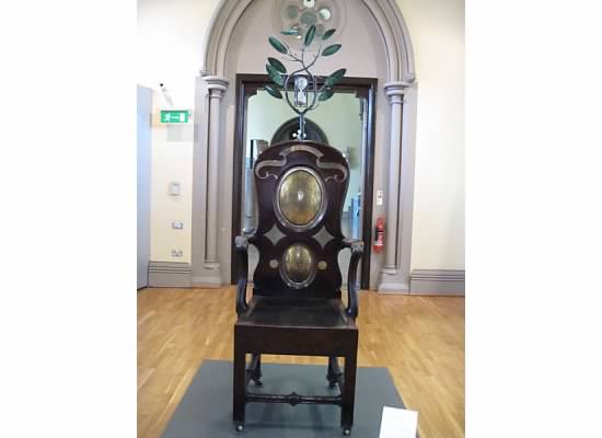 "The Blackstone Chair" -- From 1451 until the mid 19th century at the University of Glasgow, all students were examined orally seated on the Black Stone, a slab of stone. The stone was embedded in an oak chair in 1775-6. At the top is a time glass. When the sand has flowed through (20 minutes) the exam has ended. The chair is still used for the Cowan Medal exam in Classics.
